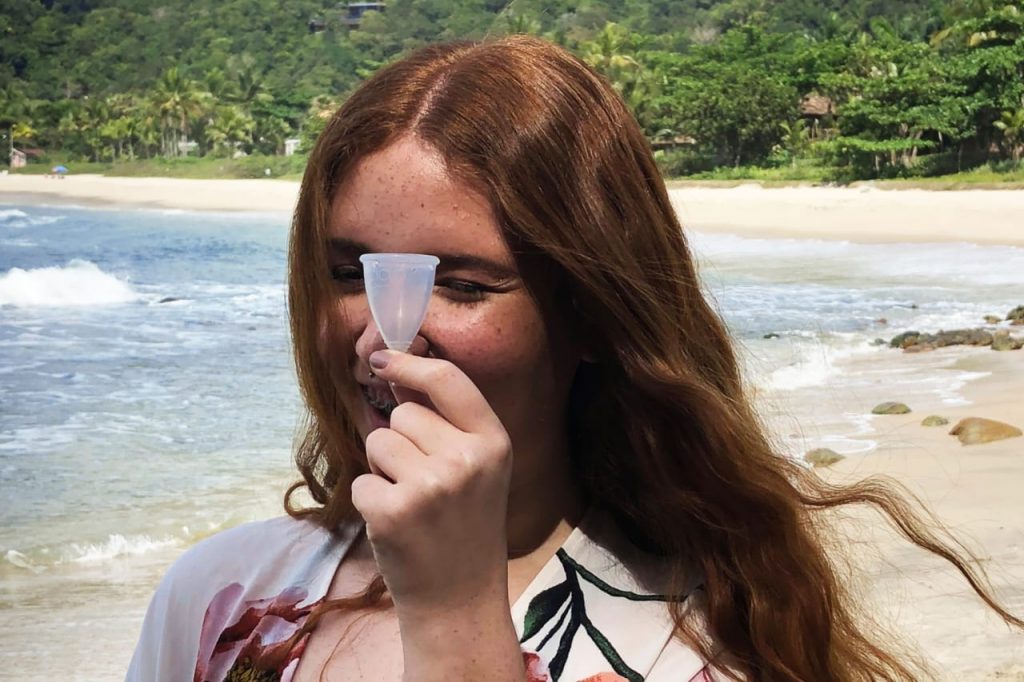 menina com coletor menstrual na praia